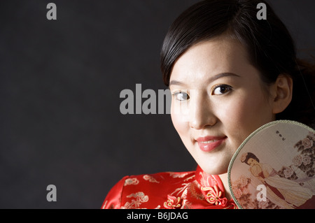 Close up of young woman in Cheongsam avec ventilateur par face posing Banque D'Images
