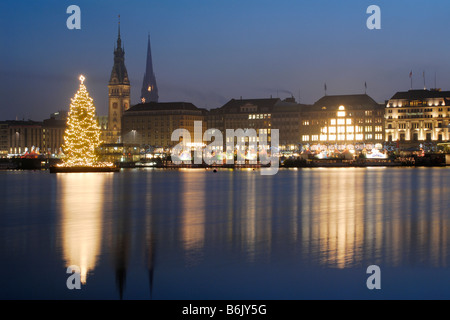 Le sapin illuminé sur l'Alster à Hambourg, en Allemagne, pendant la période de Noël. Dans l'arrière-plan l'hôtel de ville de Hambourg. Banque D'Images