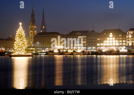 Le sapin illuminé sur l'Alster à Hambourg, en Allemagne, pendant la période de Noël. Dans l'arrière-plan l'hôtel de ville de Hambourg. Banque D'Images