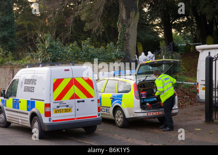 Les officiers de police judiciaire et à la recherche d'indices après qu'un crime a été commis dans un cimetière britannique Banque D'Images