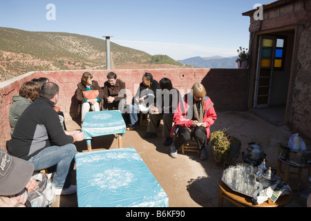 Maroc Sidi Faress Décembre groupe de touristes en attente de thé à la menthe sur toit de maison berbère traditionnelle Banque D'Images