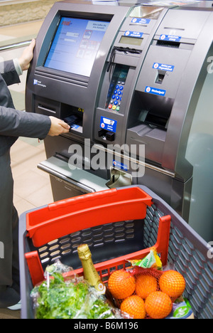 Jeune femme utilise son téléphone portable pour payer à la caisse automatique dans le véritable avenir de la partie magasin Metro Group Future Store Banque D'Images