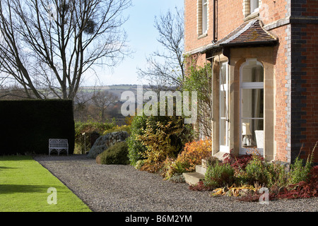 Fenêtre en baie en brique rouge de style victorien et d''une vue sur jardin d'hiver au banc blanc du gui. Banque D'Images