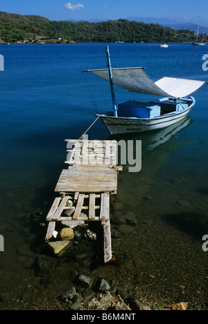 Un petit bateau amarré à une jetée en bois dans les eaux bleu calme sur la côte turquoise, Fethiye, Turquie Banque D'Images