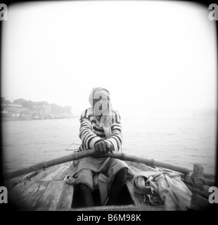 Un Varinasi boatman pour voitures rangées le long des ghats sur le Gange. Banque D'Images