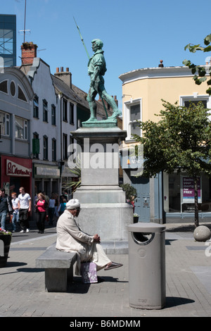 Un homme asiatique repose à côté du monument de commémoration de la rébellion de 1798 à Wexford Banque D'Images