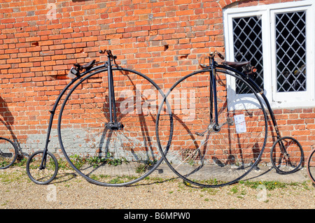 Cycles vétéran à Buckler s disque Beaulieu Hants une paire de penny farthings appuyé contre un mur de briques Banque D'Images