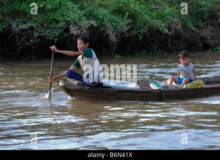 Garçon et tout-petit sampan dans le Delta du Mékong, Vietnam Banque D'Images