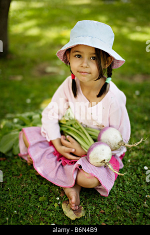 Petite fille de cinq ans tient deux navets cultivés bio Banque D'Images