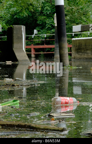 La pollution de la rivière : les bouteilles en plastique, de baignoires, de bois et de branches mortes flottant à la surface de la rivière Wey avec écluses derrière, Surrey Banque D'Images