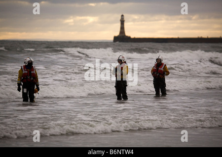 Les membres de la Royal National Lifeboat Institute (RNLI) travaillent dans la mer du Nord à Sunderland pendant le Boxing Day annuel Dip. Banque D'Images