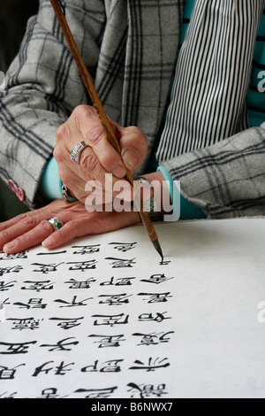 L'artiste chinois et propriétaire de boutique de la création d'une nouvelle pièce de l'oeuvre à l'aide de la calligraphie chinoise Banque D'Images