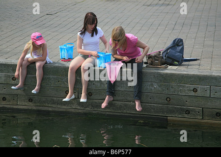 Une femme et deux enfants, étudiez le contenu de filet de pêche sur Lymington Pier Hampshire England UK Banque D'Images