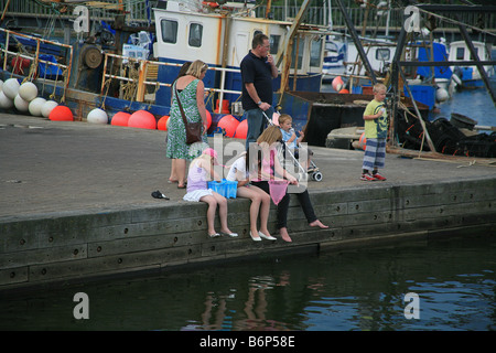 Une femme et deux enfants, étudiez le contenu de filet de pêche sur Lymington Pier Hampshire England UK Banque D'Images