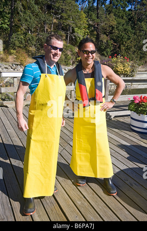 Deux visiteurs vêtus de tabliers de caoutchouc et les endurants se préparent à sortir sur un bateau prises de crabe à Salt Spring Island, Canada Banque D'Images