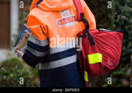 Un facteur de la Royal Mail marche sur son tour de distribuer les lettres dans l'Essex U K Banque D'Images