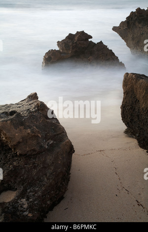 Une exposition longue, utilisé sur les vagues autour des roches côtières de produire effet misty moody Banque D'Images
