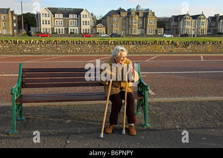 Vieille Femme assis sur un banc en fin d'après-midi, soleil d'hiver Weston Super Mare North Somerset en Angleterre Banque D'Images