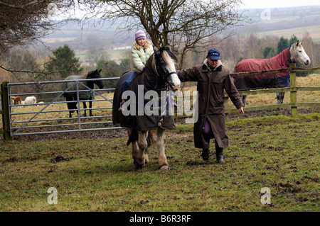 Mère à la tête d'une petite fille cheval par temps froid. Campagne anglaise UK Banque D'Images