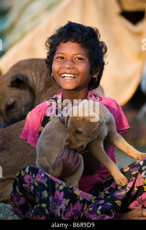 Les indiens pauvres fille jouant avec son chien chiot à l'extérieur d'une tente dans la lumière du matin Banque D'Images