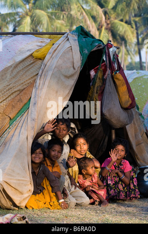 Les Indiens nomades pauvres enfants, garçons et filles, assis dans leur tente dans la lumière du soleil tôt le matin. L'Andhra Pradesh, Inde Banque D'Images