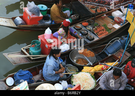 Les gens sur la vente de bateaux en bois de la nourriture aux personnes sur la banque. Le marché flottant d'Amphawa, Thaïlande Banque D'Images