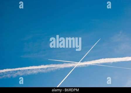 Les traînées de condensation des avions commerciaux de voler dans des directions différentes. Banque D'Images