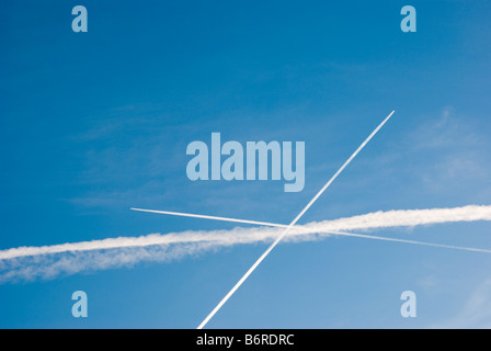 Les traînées de condensation des avions commerciaux de voler dans des directions différentes. Banque D'Images