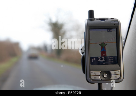 Sat Nav montrant u turn sur un pocket pc relié à un pare-brise de voiture sur une route de campagne Banque D'Images