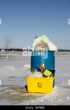 Une corbeille bleu et jaune une corbeille pleine sont assis dans la neige. Banque D'Images