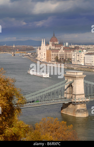 Une BARGE TOURISTIQUE PASSE SOUS LE PONT DES CHAÎNES AVEC LE PARLEMENT DE LA DISTANCE SUR LA RIVE DU DANUBE DANS Banque D'Images