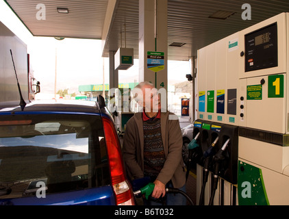 73 ans ex pat anglais de la mise à niveau de voiture avec l'essence à une station dans le Castell de Ferro, Granada, Andalousie, Espagne du sud Banque D'Images