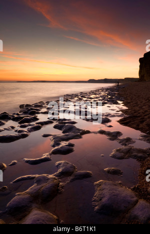 Coucher de réflexions dans des rochers sur la plage de Burton Bradstock, Dorset, England, UK Banque D'Images