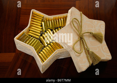 Barres d'or du chocolat suisse dans une boîte en forme d'étoile sur une table en bois Banque D'Images