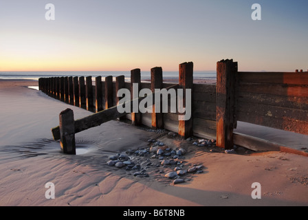 groynes en bois sur la plage de barmouth au coucher du soleil Banque D'Images