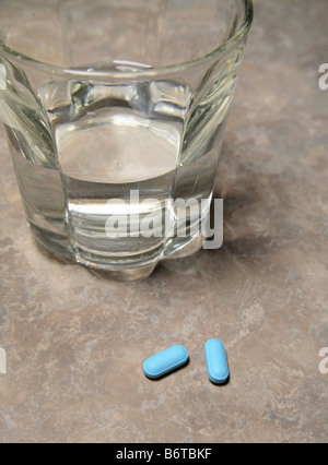 Comprimés bleu et verre d'eau sur un comptoir close-up Banque D'Images