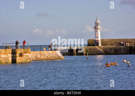 Les personnes bénéficiant du soleil d'automne sur le mur du port à Mevagissey, Cornwall Banque D'Images