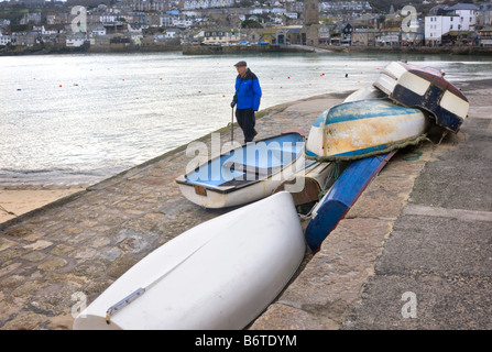 Man Walking tournée vers le passé des canots dans le port de St Ives, Cornwall Banque D'Images