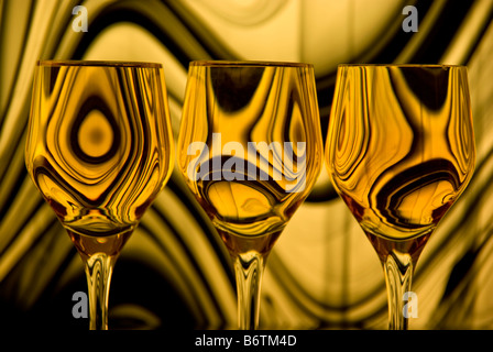 Close up de trois verres à vin avec un fond d'or et noir lignes tourbillonnantes reflète dans chaque verre. Banque D'Images