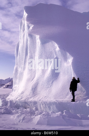 Climber sur gros iceberg dans la glace près de l'Est du Groenland Kulusuk glace cassée à la base est due à une combinaison de la marée Banque D'Images