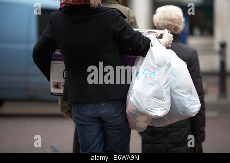 Shopper femme de porter de lourds sacs de magasinage et de colis lors de la vente au Royaume-Uni Janvier Banque D'Images