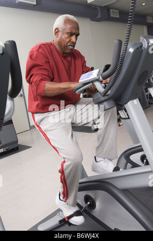 Senior Man Exercising sur vélo stationnaire Banque D'Images