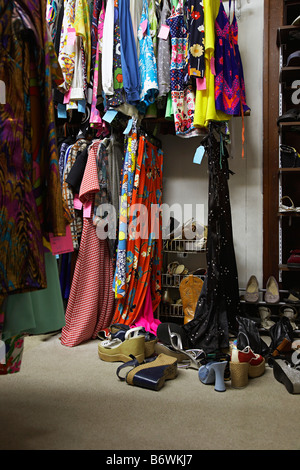 Les Racks de vêtements entassés en piles et en chaussures Magasin de seconde main Banque D'Images