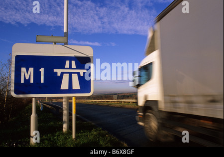 Camion passant panneau routier indiquant début de l'autoroute M1 près de Leeds Yorkshire UK Banque D'Images