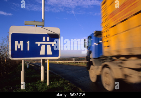 Camion passant panneau routier indiquant début de l'autoroute M1 près de Leeds Yorkshire UK Banque D'Images