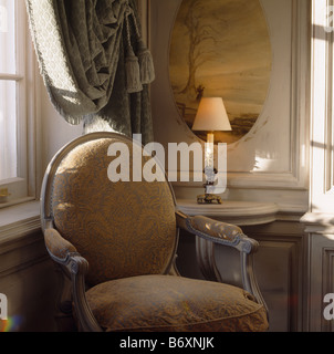 Lampe allumée et panneau peint sur table console derrière Louis IV fauteuil style Banque D'Images