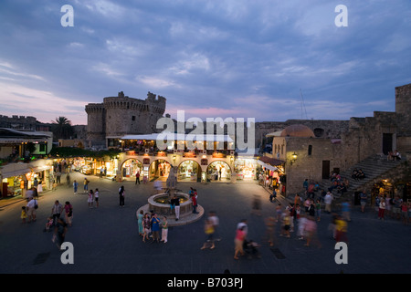 Voir plus Ippokratou Thalassini Platia occupé avec porte en arrière-plan dans la soirée, la ville de Rhodes, Rhodes, Grèce, (depuis 1988 par Banque D'Images