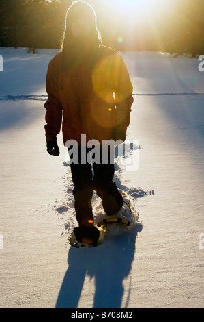 Une jeune femme en raquettes à neige fraîchement tombée au coucher du soleil dans la région de Flagstaff, Arizona. Banque D'Images