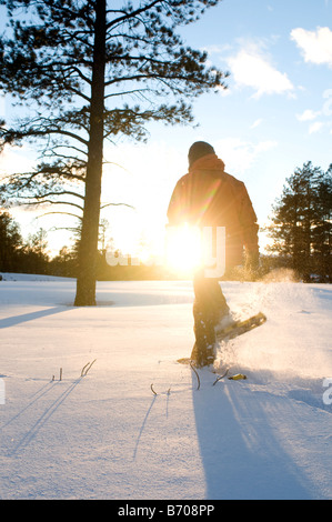 Une jeune femme en raquettes à neige fraîchement tombée au coucher du soleil dans la région de Flagstaff, Arizona. Banque D'Images