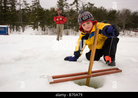 Les chèques d'un garçon, tandis que les pièges de la pêche sur glace sur le lac du Maine dans le Nord Waterboro, Maine. Banque D'Images